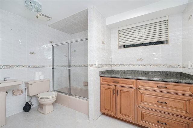 full bathroom with shower / bath combination with glass door, tile patterned floors, visible vents, toilet, and tile walls