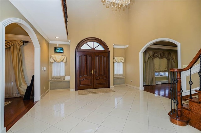 tiled foyer entrance with baseboards, arched walkways, and crown molding