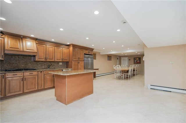 kitchen featuring black gas cooktop, a sink, a center island, stainless steel fridge, and baseboard heating