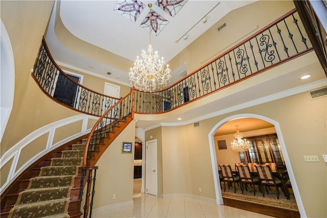 staircase featuring arched walkways, visible vents, a towering ceiling, and a notable chandelier