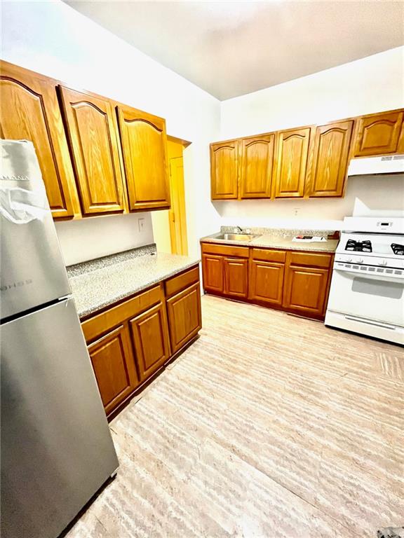 kitchen featuring sink, stainless steel fridge, light hardwood / wood-style floors, and white gas range oven