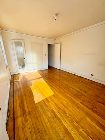 unfurnished bedroom with wood-type flooring and ornamental molding