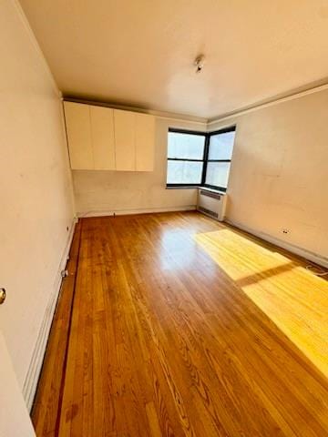 empty room with ornamental molding and light wood-type flooring