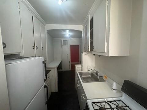 kitchen with fridge, white cabinetry, sink, and white range with gas stovetop