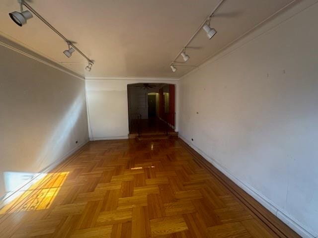 hall with ornamental molding, rail lighting, and baseboards