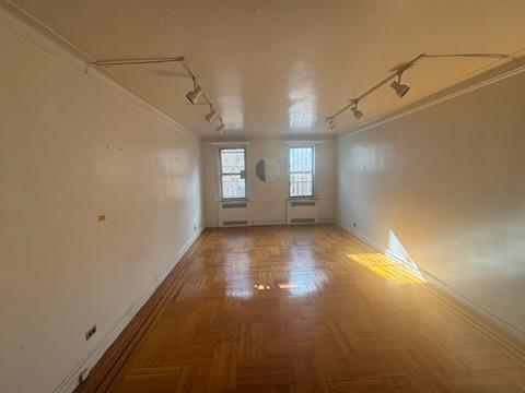 empty room featuring ornamental molding, parquet flooring, and rail lighting