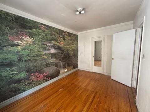 empty room featuring hardwood / wood-style flooring and ornamental molding