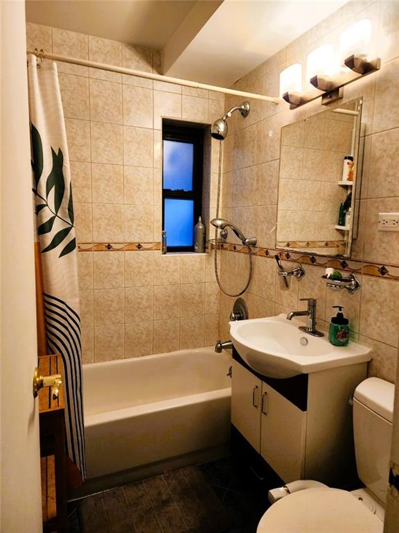 full bathroom with tile walls, backsplash, vanity, toilet, and shower / bath combo with shower curtain