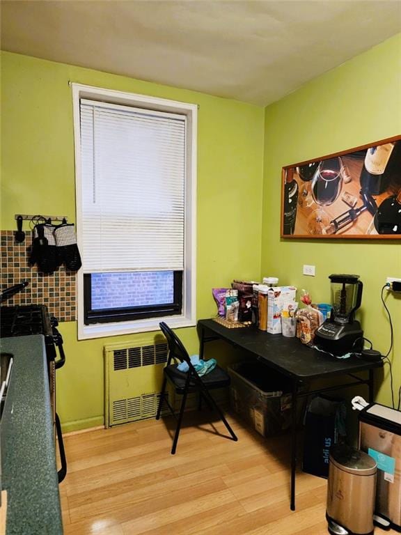 home office with radiator, a wealth of natural light, and light hardwood / wood-style floors