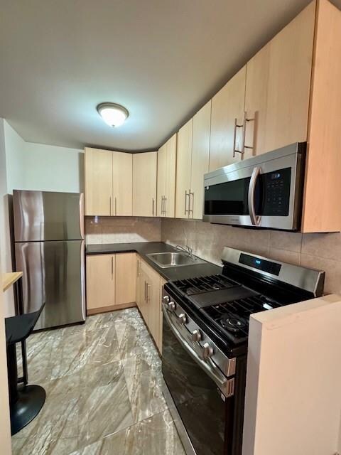 kitchen featuring light brown cabinetry, sink, backsplash, and stainless steel appliances