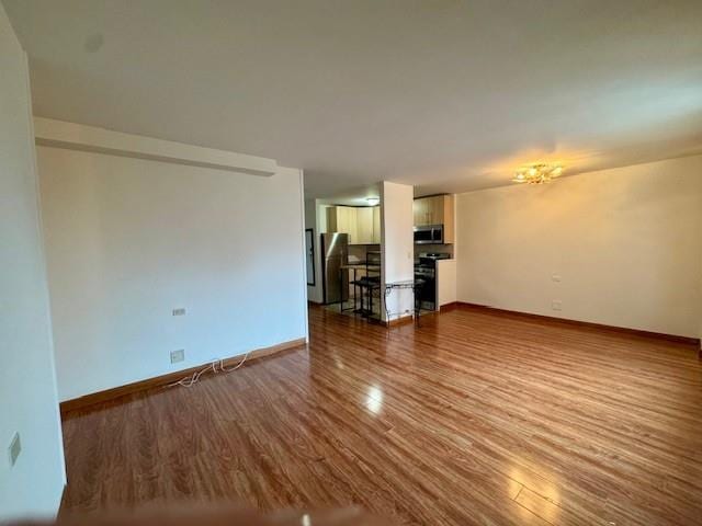 unfurnished living room with baseboards and wood finished floors