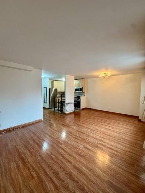 unfurnished living room featuring baseboards and wood finished floors