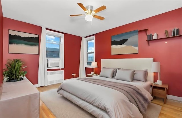 bedroom featuring radiator heating unit, ceiling fan, and light wood-type flooring