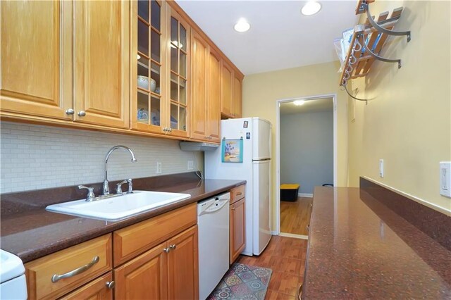 kitchen featuring tasteful backsplash, white appliances, dark stone counters, and sink