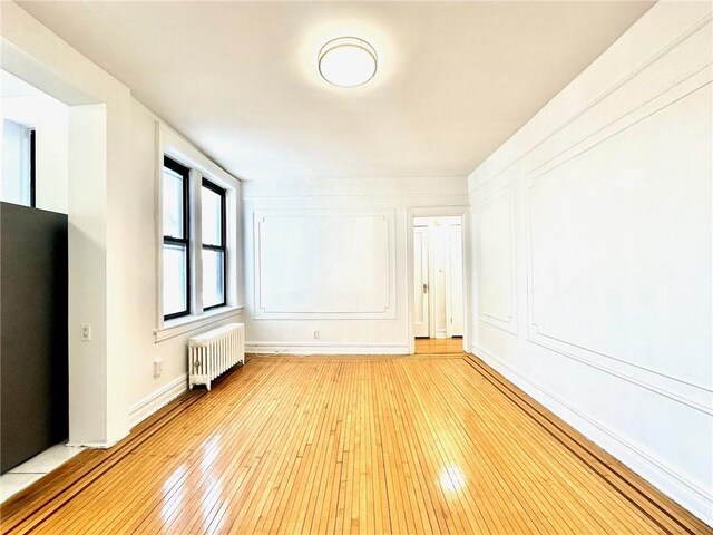 additional living space featuring radiator and light wood-type flooring