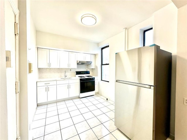 kitchen featuring freestanding refrigerator, a sink, light countertops, under cabinet range hood, and white gas range