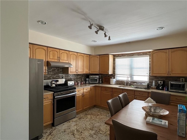 kitchen featuring stainless steel appliances, a sink, a toaster, tasteful backsplash, and under cabinet range hood