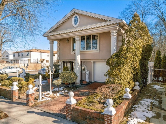 greek revival inspired property with stucco siding and an attached garage