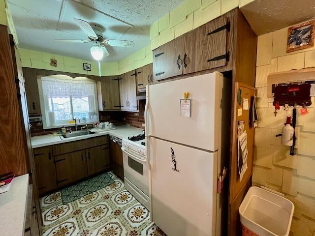 kitchen with light countertops, a ceiling fan, a sink, a textured ceiling, and white appliances