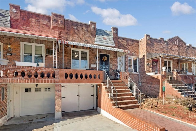 view of property featuring stairs, concrete driveway, brick siding, and a garage