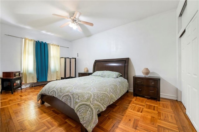 bedroom featuring a closet, baseboards, ceiling fan, and a wood stove