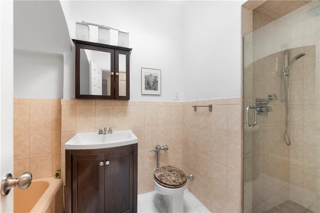 full bathroom with tile walls, toilet, a stall shower, wainscoting, and vanity