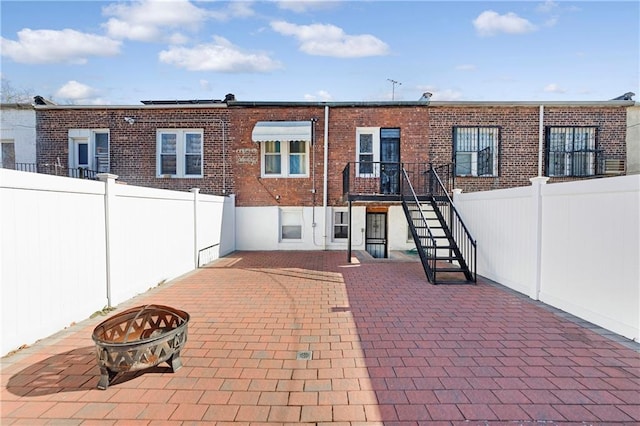 rear view of property featuring an outdoor fire pit and a patio