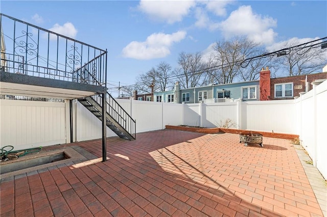 view of patio featuring an outdoor fire pit, a fenced backyard, and stairs