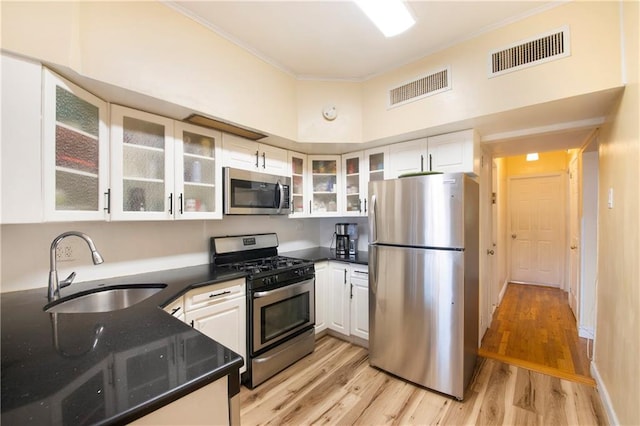 kitchen with appliances with stainless steel finishes, visible vents, a sink, and crown molding