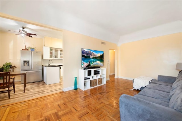 living area featuring visible vents, ceiling fan, and baseboards