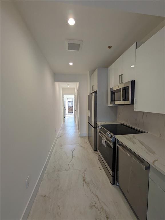 122 Palmetto St Unit 3L, Brooklyn, NY 11221 - kitchen with appliances with stainless steel finishes, baseboards, light stone counters, white cabinets, and recessed lighting
