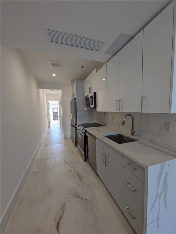 kitchen featuring tasteful backsplash, sink, white cabinets, stainless steel appliances, and light stone countertops