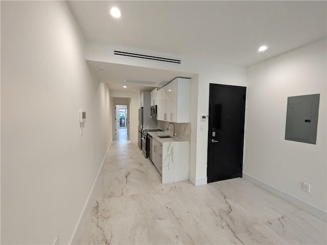 kitchen featuring sink, white cabinetry, backsplash, electric panel, and stainless steel appliances