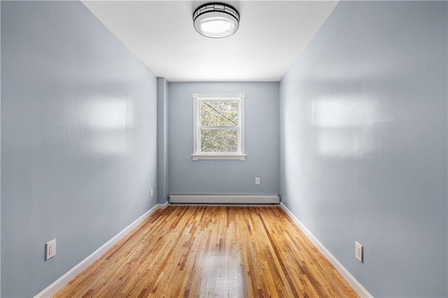 unfurnished room with a baseboard heating unit and light wood-type flooring