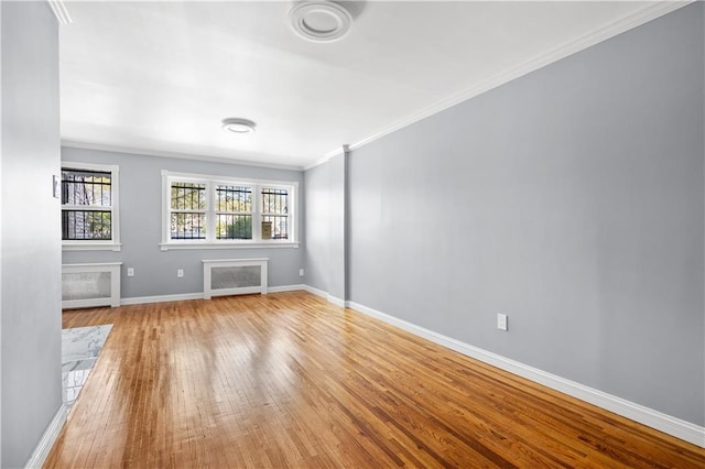 spare room with light wood finished floors, baseboards, and ornamental molding