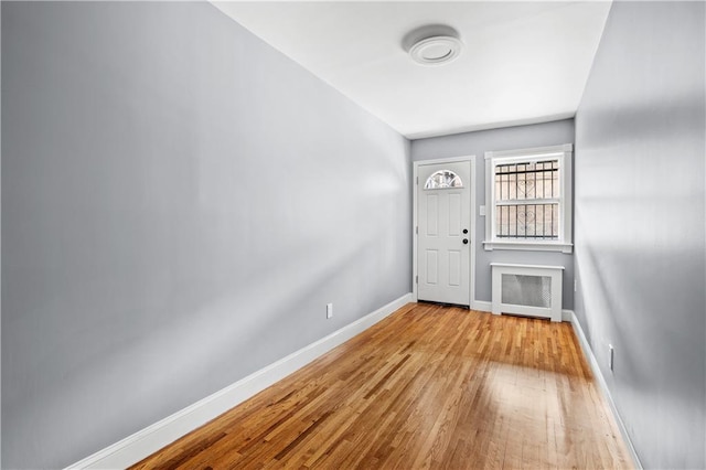 foyer entrance with radiator, wood finished floors, and baseboards