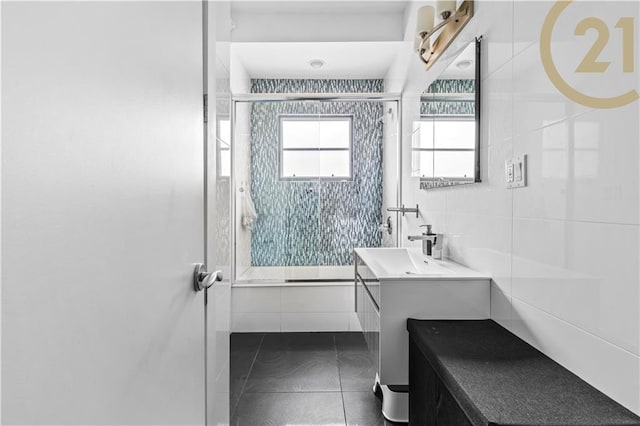 full bath featuring tiled shower, tile walls, vanity, and tile patterned floors