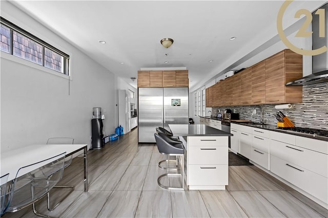 kitchen with dark countertops, appliances with stainless steel finishes, white cabinets, a kitchen island, and modern cabinets