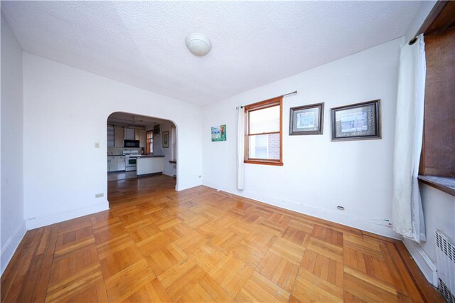 spare room featuring light parquet floors and a textured ceiling