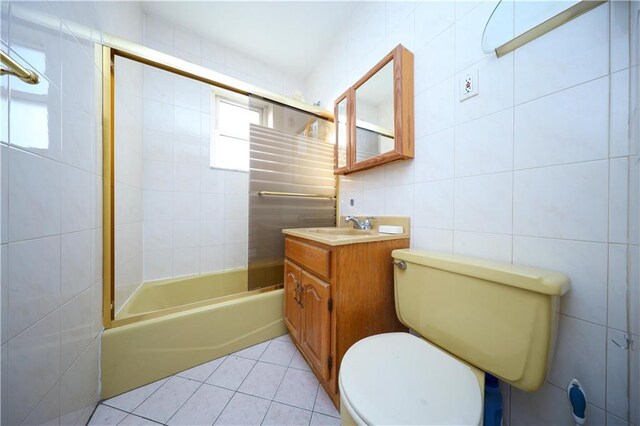 full bathroom with tile walls, tiled shower / bath combo, vanity, tile patterned floors, and toilet