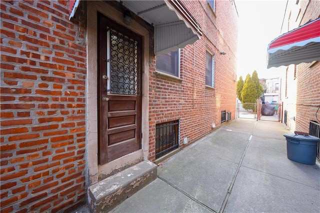 property entrance with a gate, fence, and brick siding