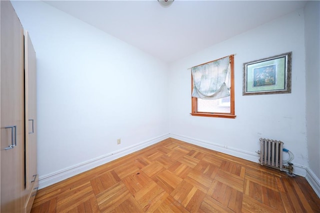 unfurnished room featuring radiator heating unit and baseboards