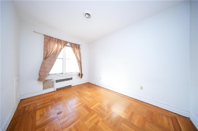 spare room with radiator heating unit and baseboards