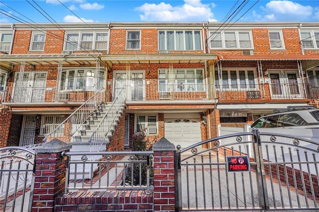 view of property featuring stairway, a gate, brick siding, and a fenced front yard