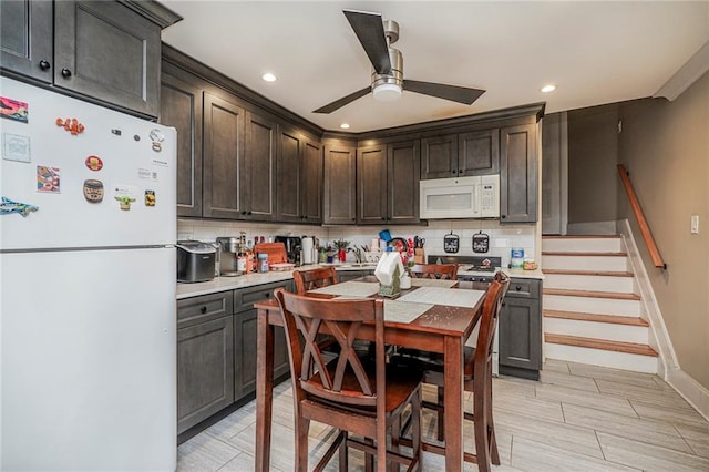 kitchen featuring white appliances, dark brown cabinetry, light countertops, decorative backsplash, and ceiling fan