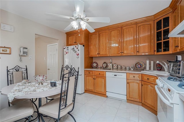 kitchen featuring glass insert cabinets, white appliances, light countertops, and a sink