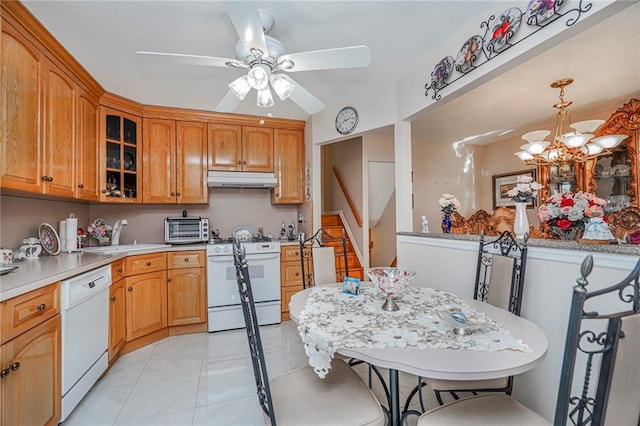 kitchen with white appliances, a sink, glass insert cabinets, under cabinet range hood, and ceiling fan with notable chandelier