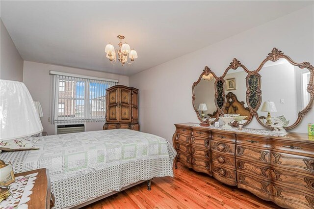 bedroom featuring wood finished floors, a wall mounted air conditioner, and a chandelier