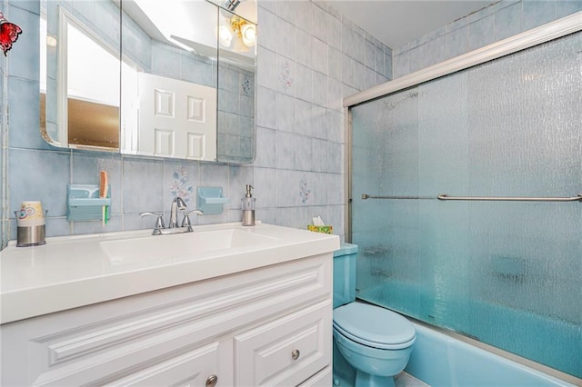 full bath with tasteful backsplash, toilet, vanity, enclosed tub / shower combo, and tile walls