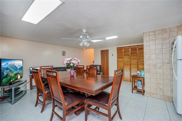 dining area with light tile patterned flooring, a ceiling fan, and a textured ceiling